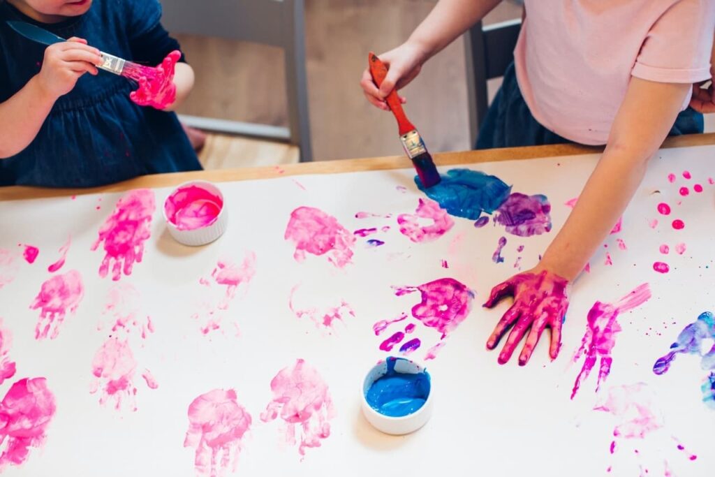 children with paint making a hand print picture