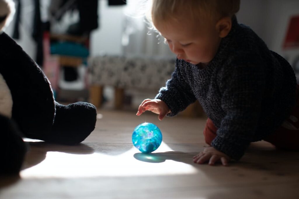 A baby playing with a bright blue ball
