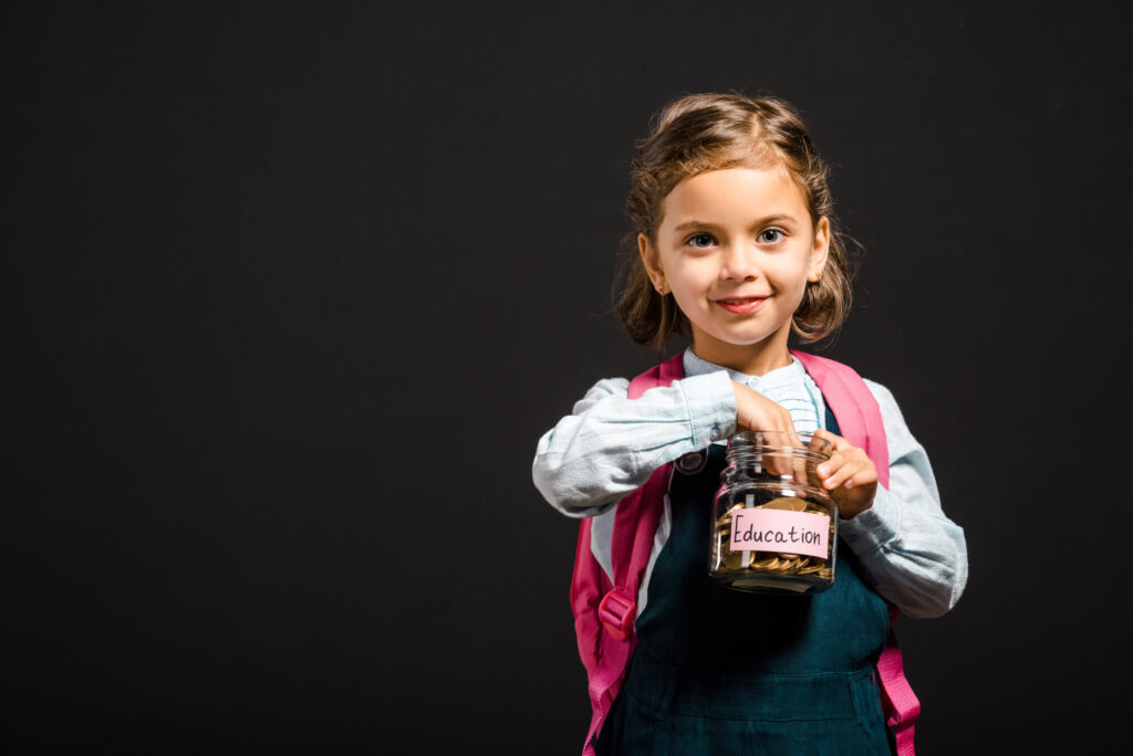 A child placing a coin into a jar labelled education