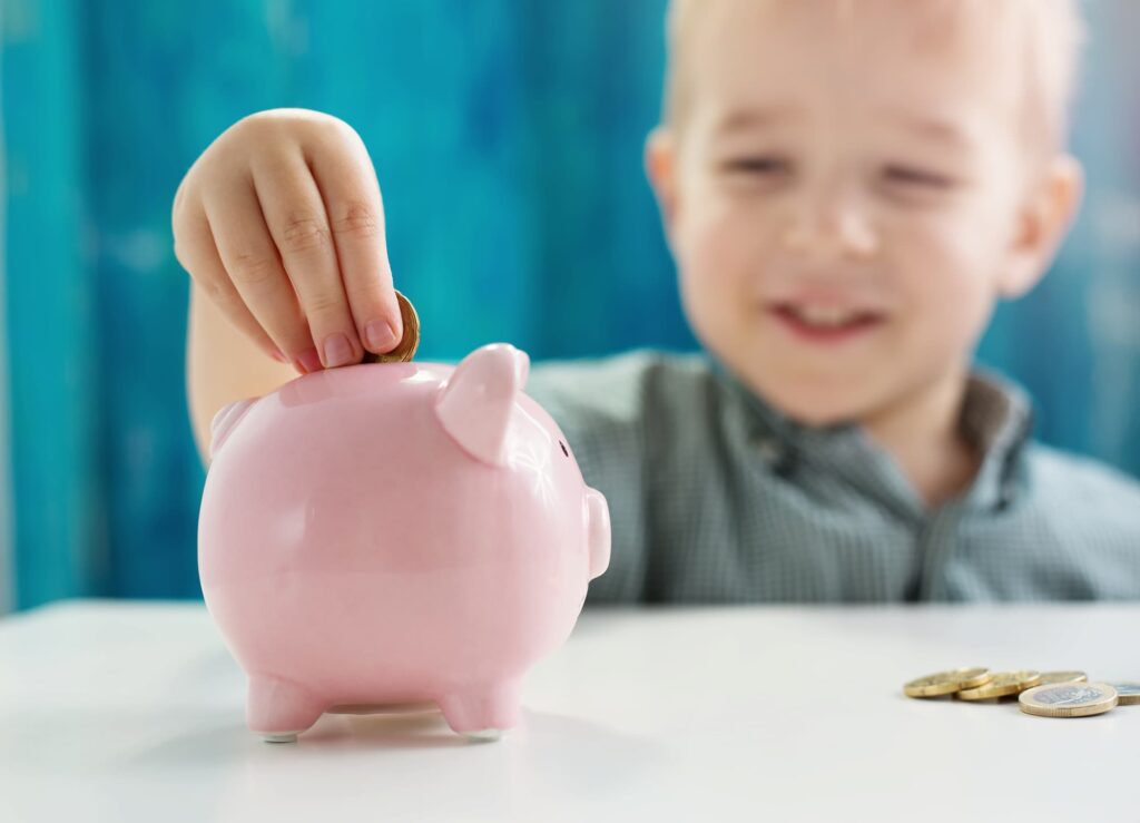 A child putting coins into a piggy bank.